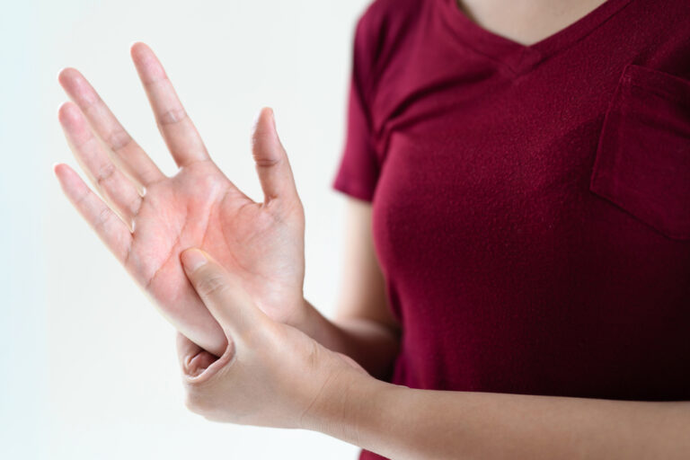 Relief for Neuropathy Pain - N8 Family Chiropractic Person in a burgundy shirt checks their pulse by feeling the inside of their wrist on one hand with the other hand calm nearby.